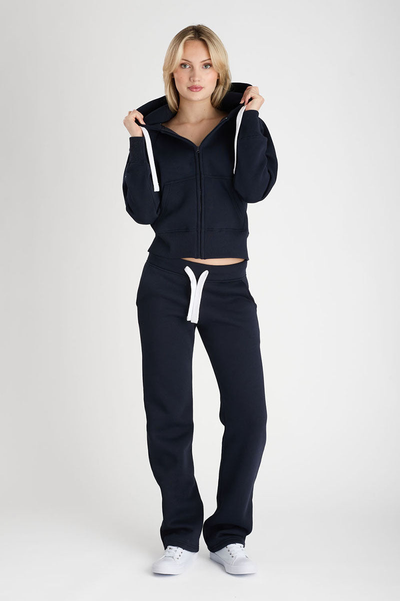 Woman wearing a navy tracksuit with white drawstrings on a white background