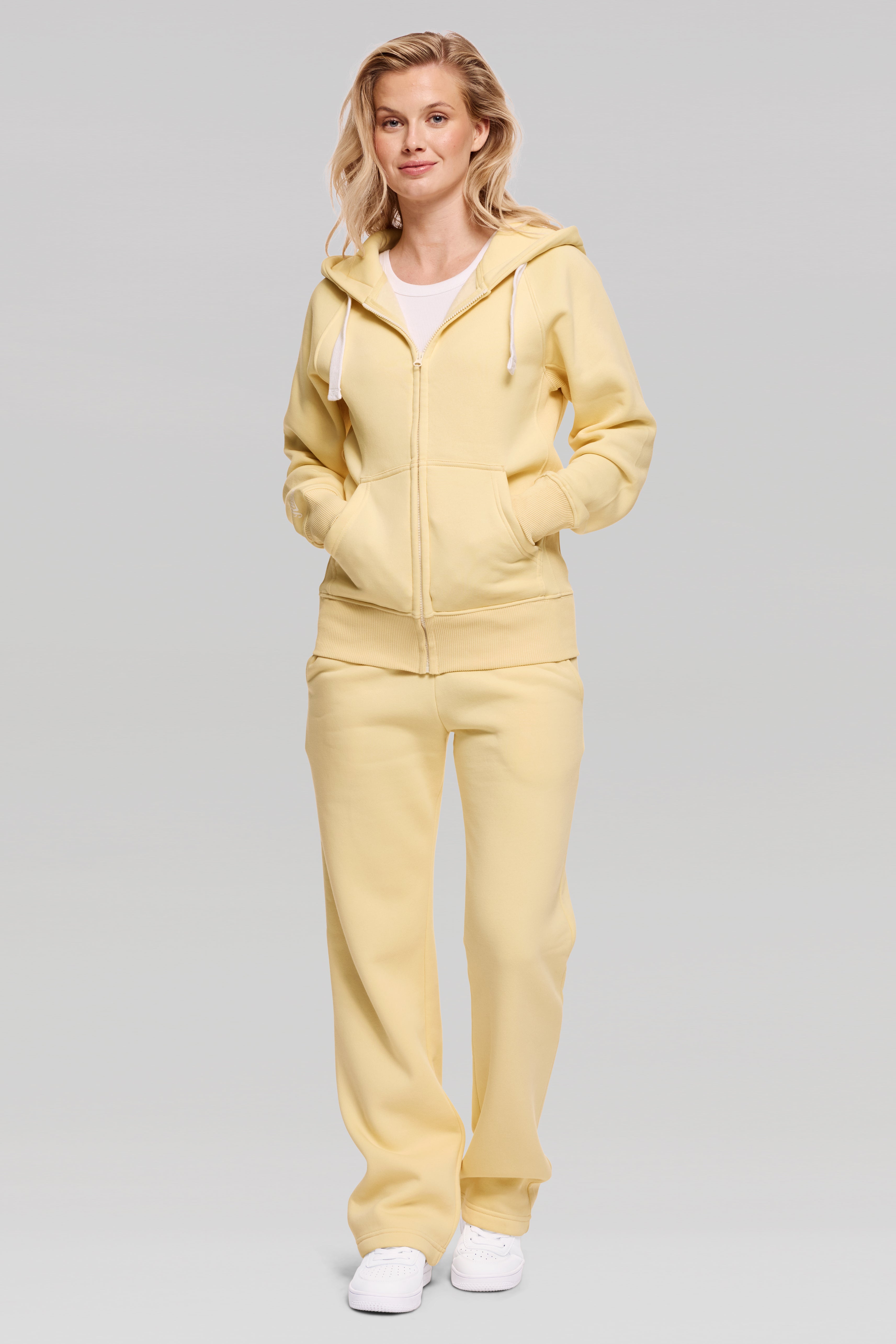 Woman wearing a yellow tracksuit on a gray background