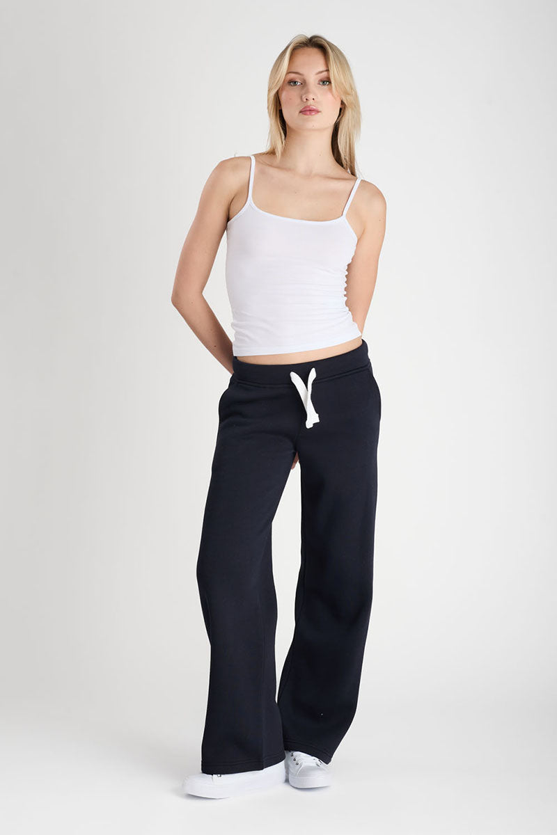 Woman wearing a white tank top and dark navy drawstring pants on a white background