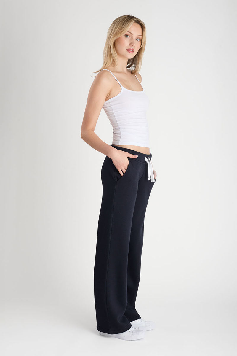 Woman wearing a white tank top and dark navy pants on a white background