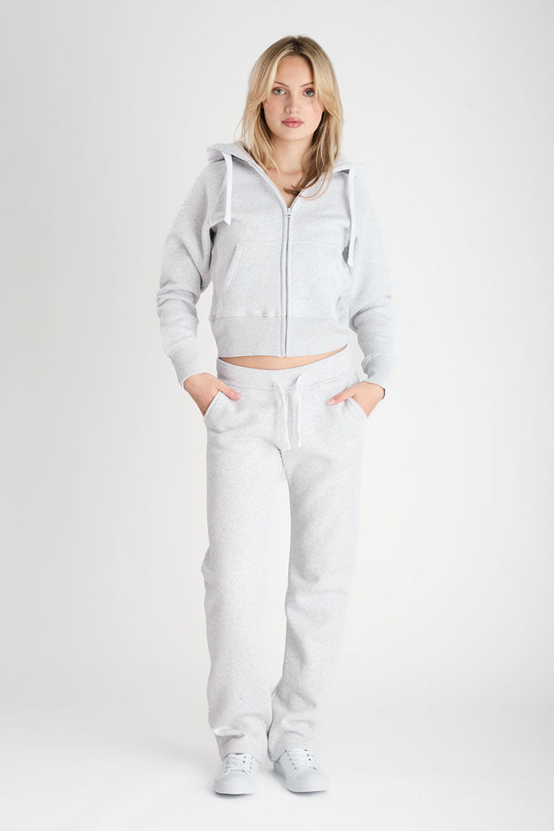 Woman wearing a light gray hoodie and pants on a white background