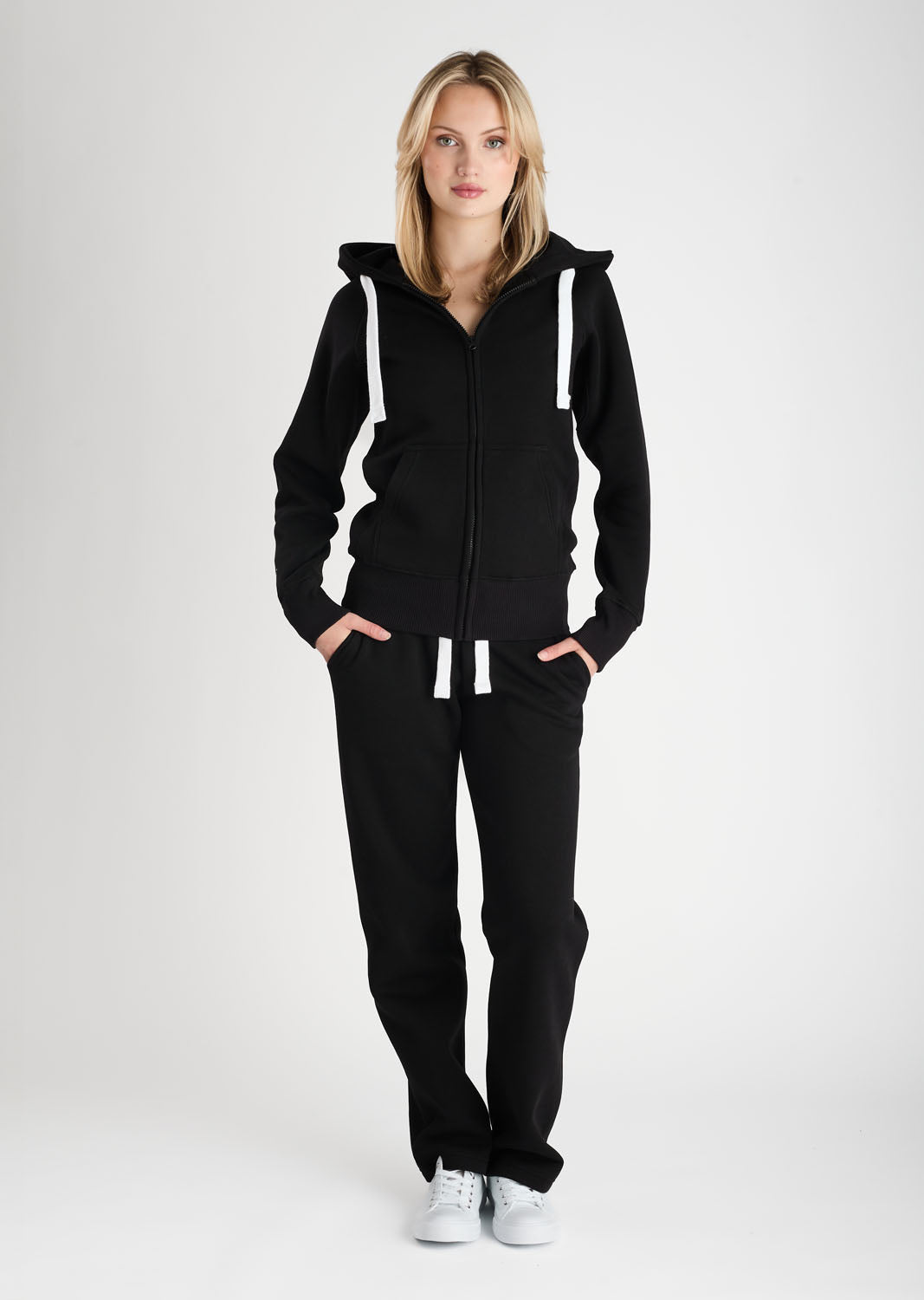 Woman wearing a black tracksuit with white stripes on a white background