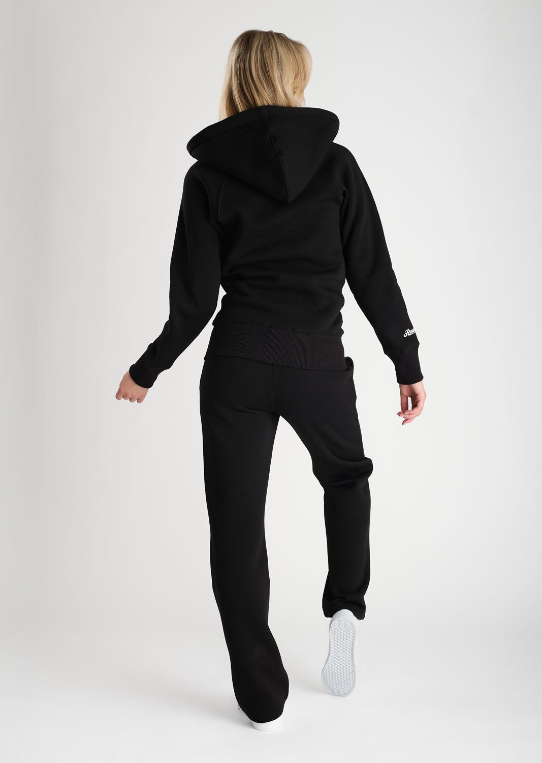 Person wearing a black tracksuit on a white background
