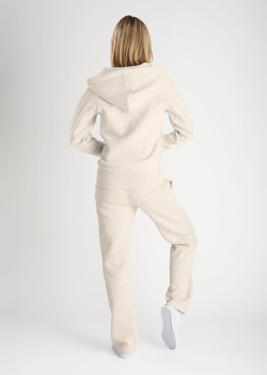 Person wearing a beige tracksuit on a white background