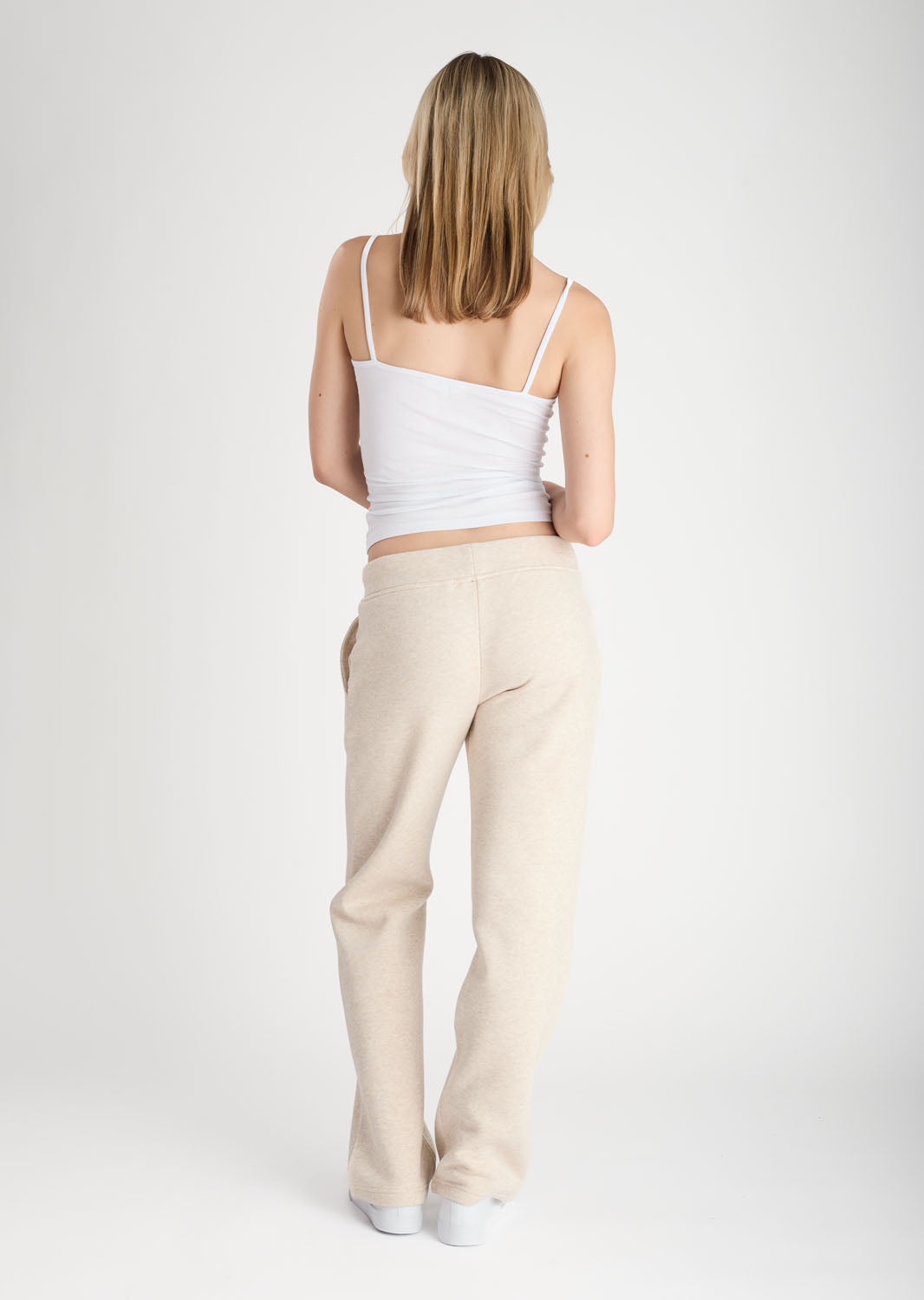 Woman wearing a white top and beige pants on a white background