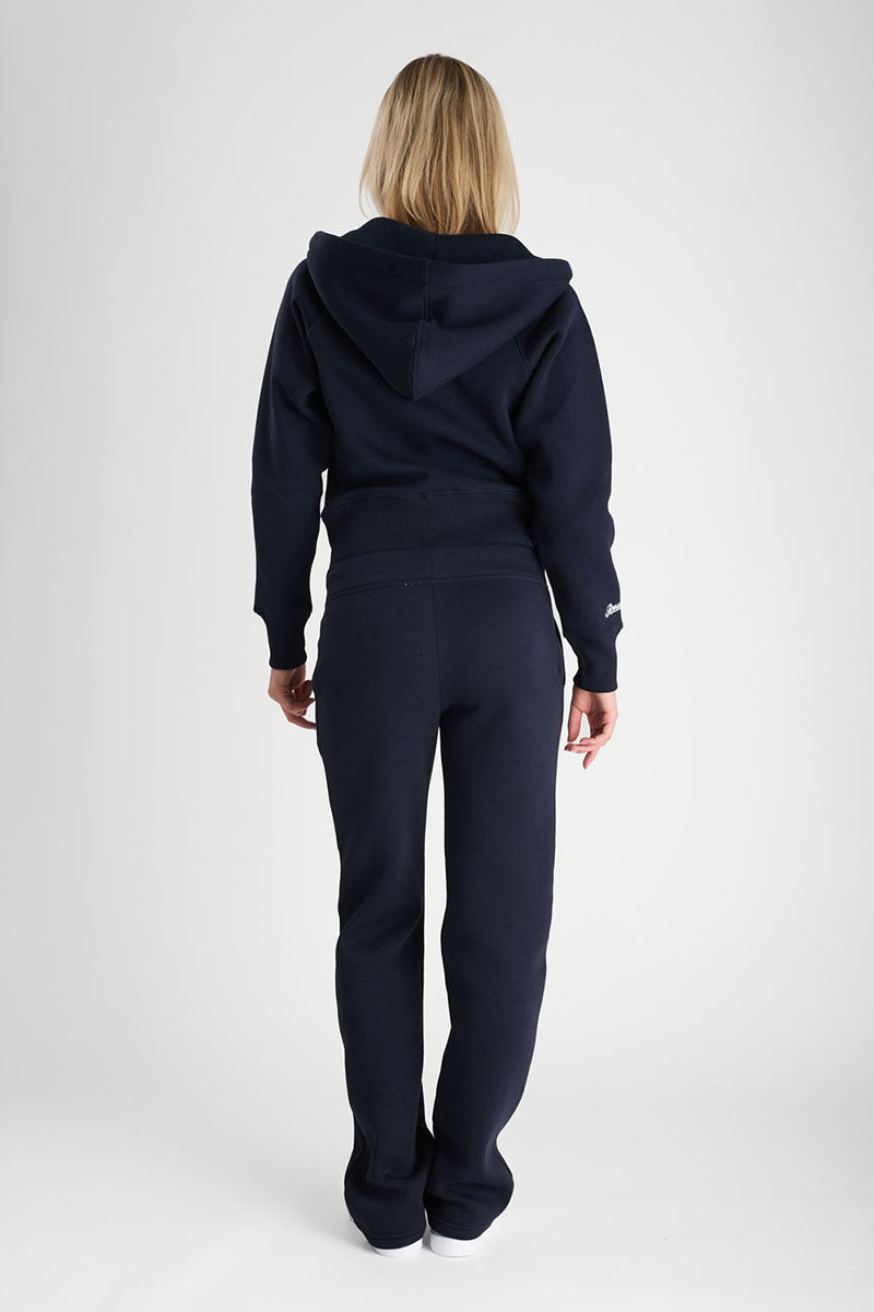 Person wearing a navy tracksuit on a white background