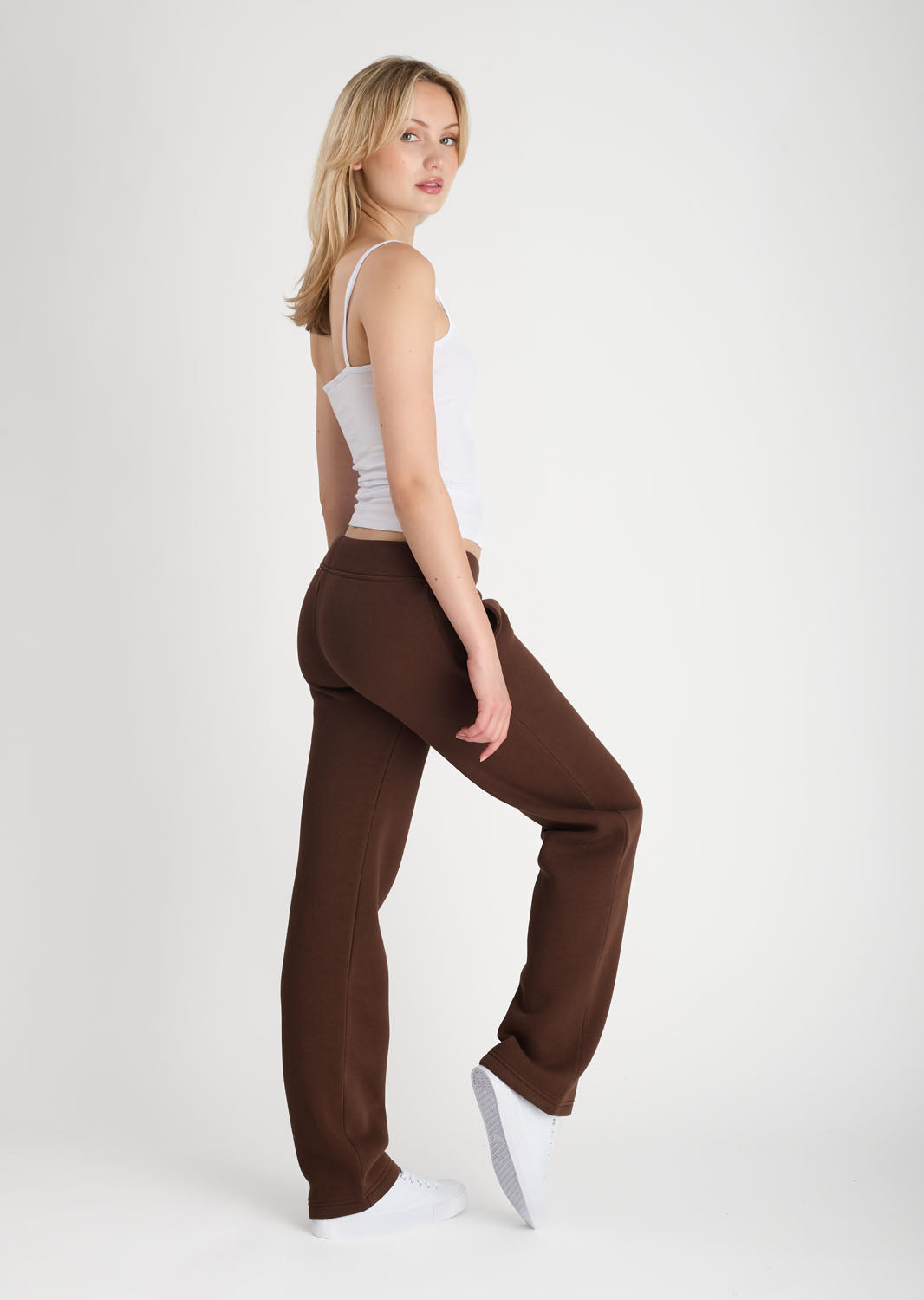 Woman wearing brown pants and a white top on a white background