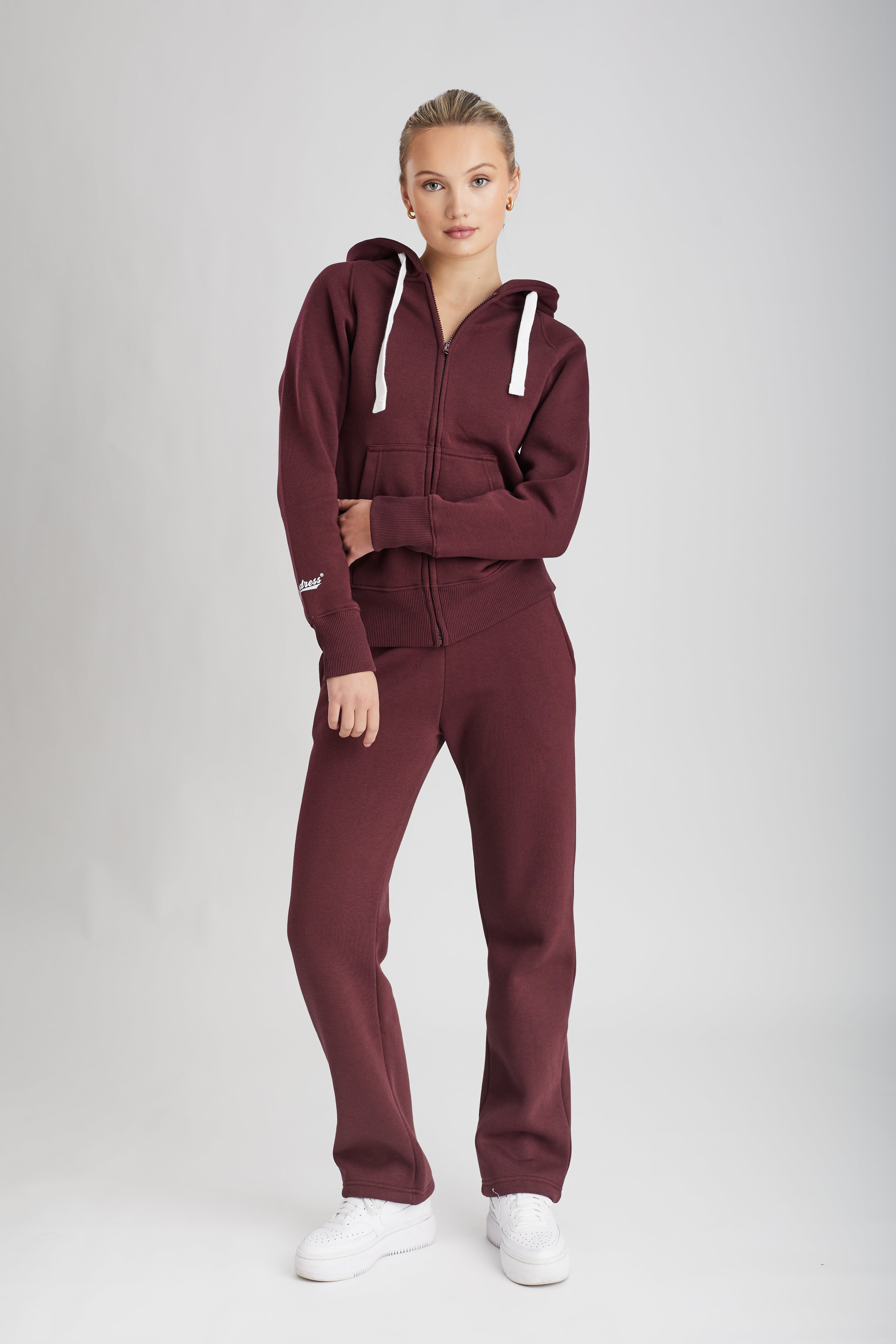 Woman wearing a maroon red tracksuit on a white background