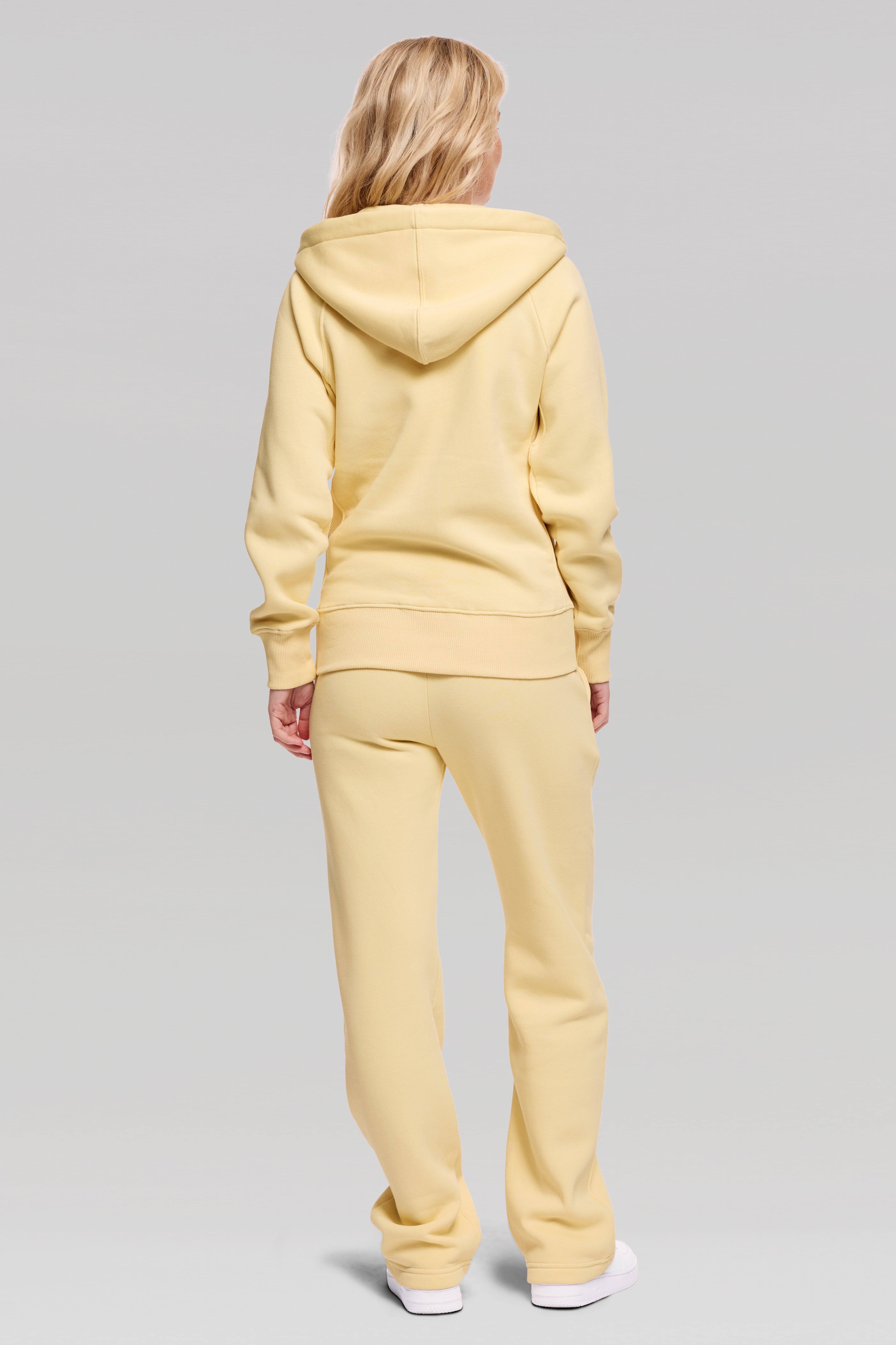 Person wearing a yellow tracksuit on a gray background
