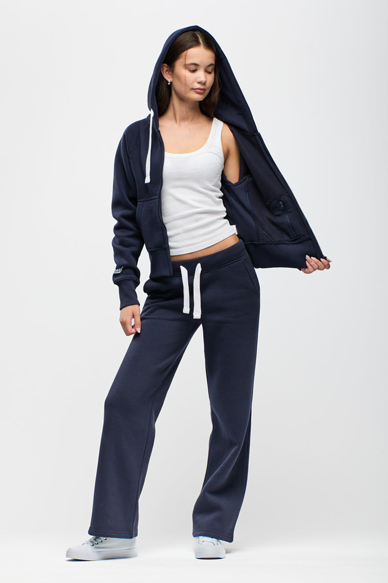 Woman wearing a navy tracksuit with a white top on a white background